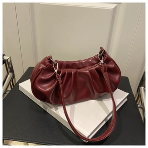 Detail of burgundy ruched cloud bag with leather texture and silver metal hardware