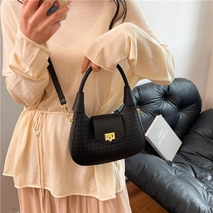 Chic black woven leather crescent handbag with gold hardware shown in an elegant lifestyle setting