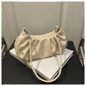 Detail of creamy pleated shoulder bag texture with silver metal buckles on book