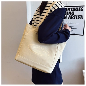 Close-up of beige canvas tote bag side pocket and TAIMEIBAG typography detail