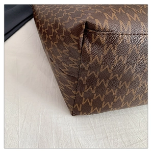 Detailed close-up of dark brown tote bag base featuring a repeat M-pattern and precise stitching