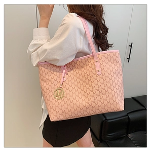 Detail of pink monogram tote bag with gold M charm and leather strap on model