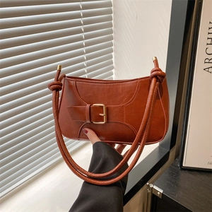 Détail du sac bandoulière en similicuir marron rouge avec boucle dorée et décor de nœuds