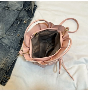 Detail view of pink ruffled bucket bag with magnetic closure and gray fabric lining