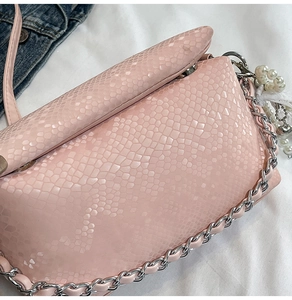 Detail of pink snake skin texture shoulder bag with silver chain and pearl heart pendant