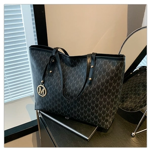 Close-up of grey monogram tote bag with gold M pendant and leather handles