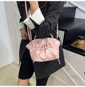 Close-up of pink pleated cloud bag with bow detail on a shoulder strap for women