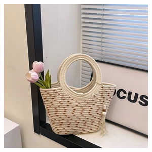 Detailed macro view of a beige woven tote bag with a round handle and fringe tassel