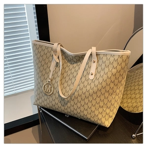 Macro shot of apricot tote bag with letter print pattern and gold metallic M charm