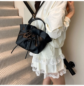 Detail of black pleated cloud bag with large bow and detachable shoulder strap