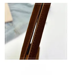 Detail of dark brown suede shoulder strap with precise stitching on vintage baguette bag