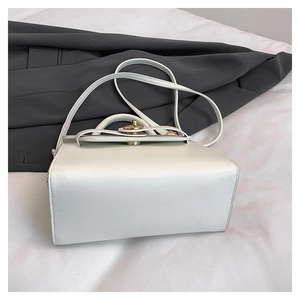 Close-up of elegant white handbag with golden twist lock and textured surface detail