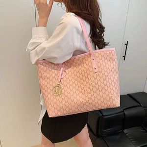 Pink large tote bag with M-letter print and gold charm shown on a shoulder