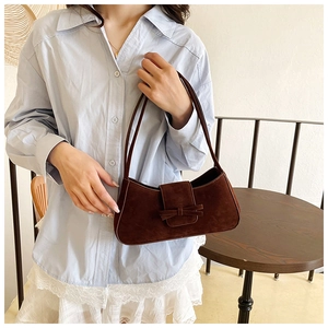 Detail of dark brown suede shoulder bag featuring a minimalist bow buckle accent