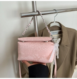 Detail of pink snake-embossed bag with silver chain and lace pearl pendant decor