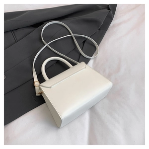 Close-up of white crossbody bag with smooth leather texture and golden adjustment buckle