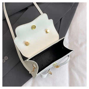 Top view of open white faux leather handbag showing interior space and gold metal locks