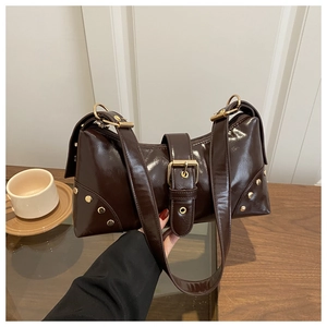 Détail du sac en cuir verni marron foncé avec boucles dorées et rivets décoratifs