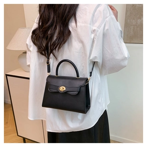 Detail of classic black leather handbag with a gold metal twist lock and top handle