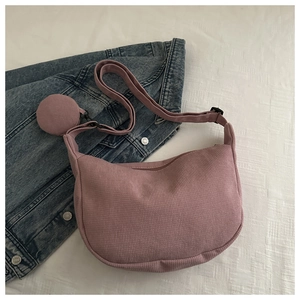 Detail of a pink corduroy crescent bag featuring vertical texture and a small coin purse