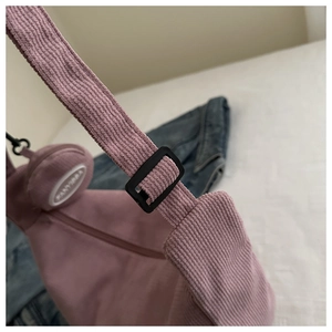 Detail of pink corduroy shoulder bag with black adjustable strap and mini round purse