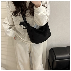Detail of black corduroy hobo bag featuring wide adjustable strap and round coin purse