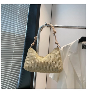 Detail of hand-woven straw tote with leather shoulder strap featuring decorative knots