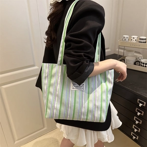 Large striped tote bag in green and purple bubble fabric carried over the shoulder
