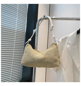 Detail of woven straw tote bag featuring white slim straps with elegant knot design