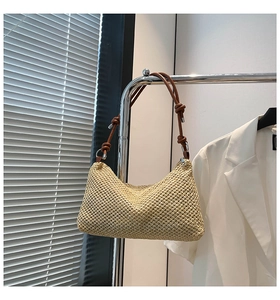 Detail of woven straw tote bag featuring brown leather knotted shoulder strap design