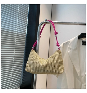 Detailed weave texture of straw tote bag with vibrant magenta knotted shoulder handle