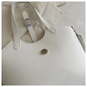 Detailed close-up of white leather tote bag with magnetic clasp and silver metal hardware