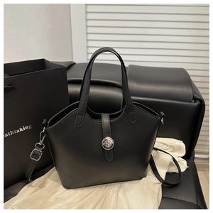 Detail of black matte leather bucket bag featuring silver logo buckle and crossbody strap
