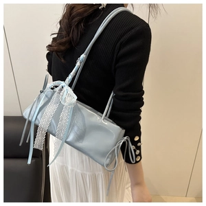 Detail of light blue glossy shoulder bag featuring a delicate white lace ribbon bow