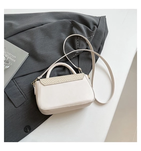Detail of cream leather shoulder bag with yellow woven straw flap on a grey suit blazer