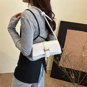 Bolso de hombro trenzado blanco con cierre H dorado y correa anudada sobre una modelo