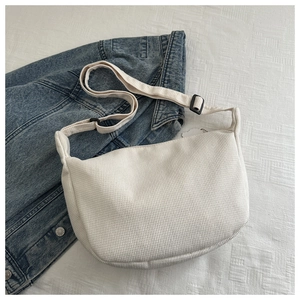 Detail view of cream white corduroy crescent bag with adjustable fabric shoulder strap