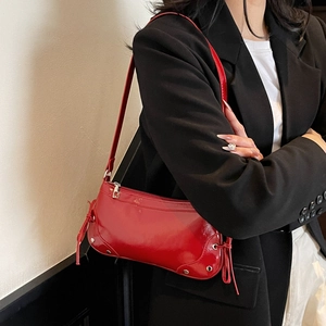 Red glossy leather underarm bag with silver studs and tassel detail on black blazer