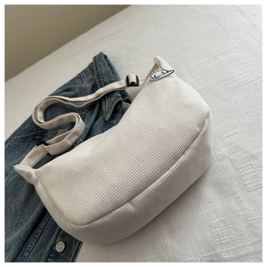 Close-up of white waffle texture crescent bag with cute dog patch on denim background