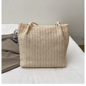 Detailed view of beige straw tote bag featuring vertical woven texture and fabric handles