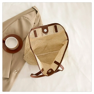 Top view of large straw tote with brown leather handles and magnetic closure detail