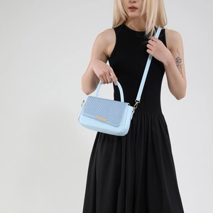 Light blue crossbody bag with chevron pattern and gold buckle on a black dress model