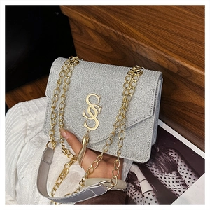 Detail of silver sequin bag featuring gold SS metal logo and elegant fringe tassel