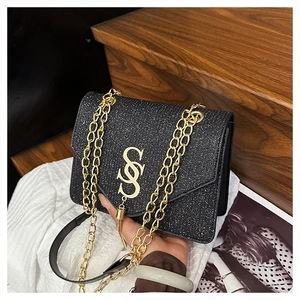 Detail of black sequined shoulder bag with golden S-logo and metal chain strap