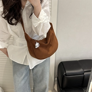 Brown corduroy crescent crossbody tote bag worn by model in a minimalist home setting