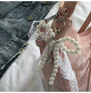 Detail of elegant pearl bow lace bag pendant with silver lobster clasp and heart charm