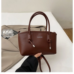 Dettaglio della borsa in pelle marrone con spalline annodate e scritte fashion