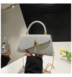Détail du sac gris argenté avec rabat à paillettes et boucle métallique dorée en V