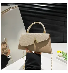 Détail des paillettes champagne et de la boucle en métal en V sur un sac à main chic