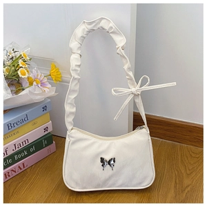 Détail du sac baguette blanc cottagecore avec fermoir papillon et bandoulière à volants